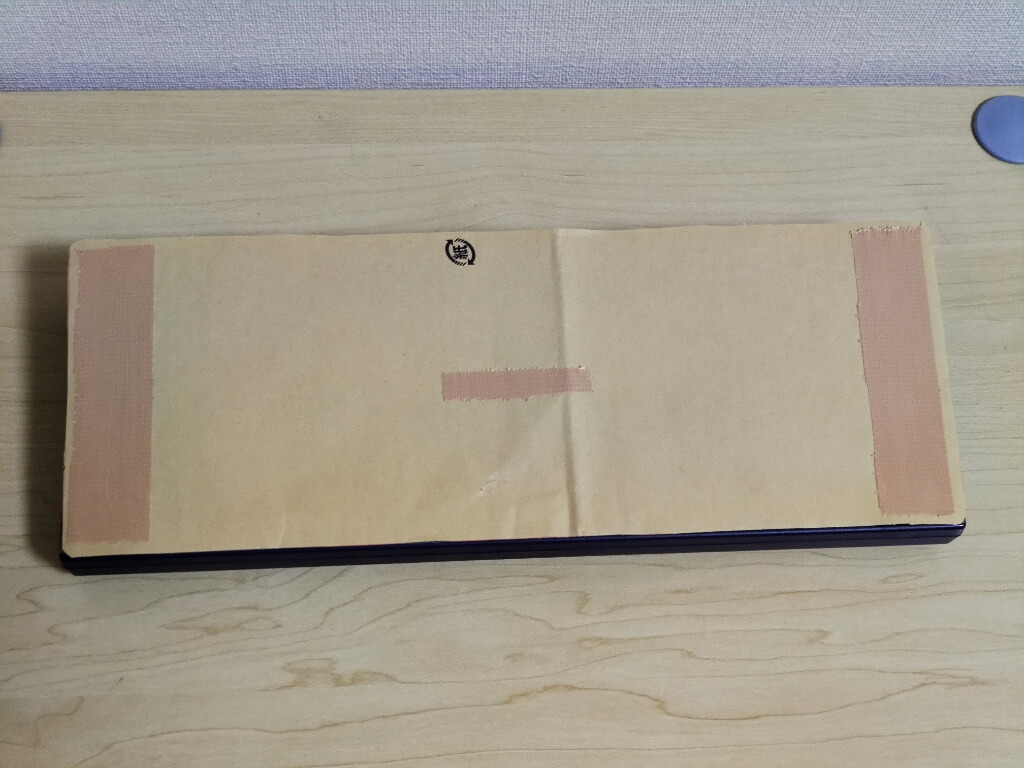 Amazonの封筒型梱包材をHHKBの裏側に貼り付けた上にガムテープを貼ったところ